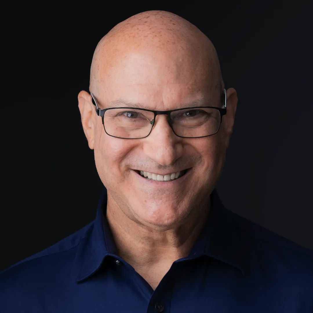 man with glasses and a blue shirt smiling at the camera